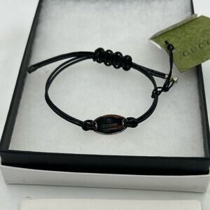 Gucci, black leather cord bracelet with sterling silver logo engraved plaque